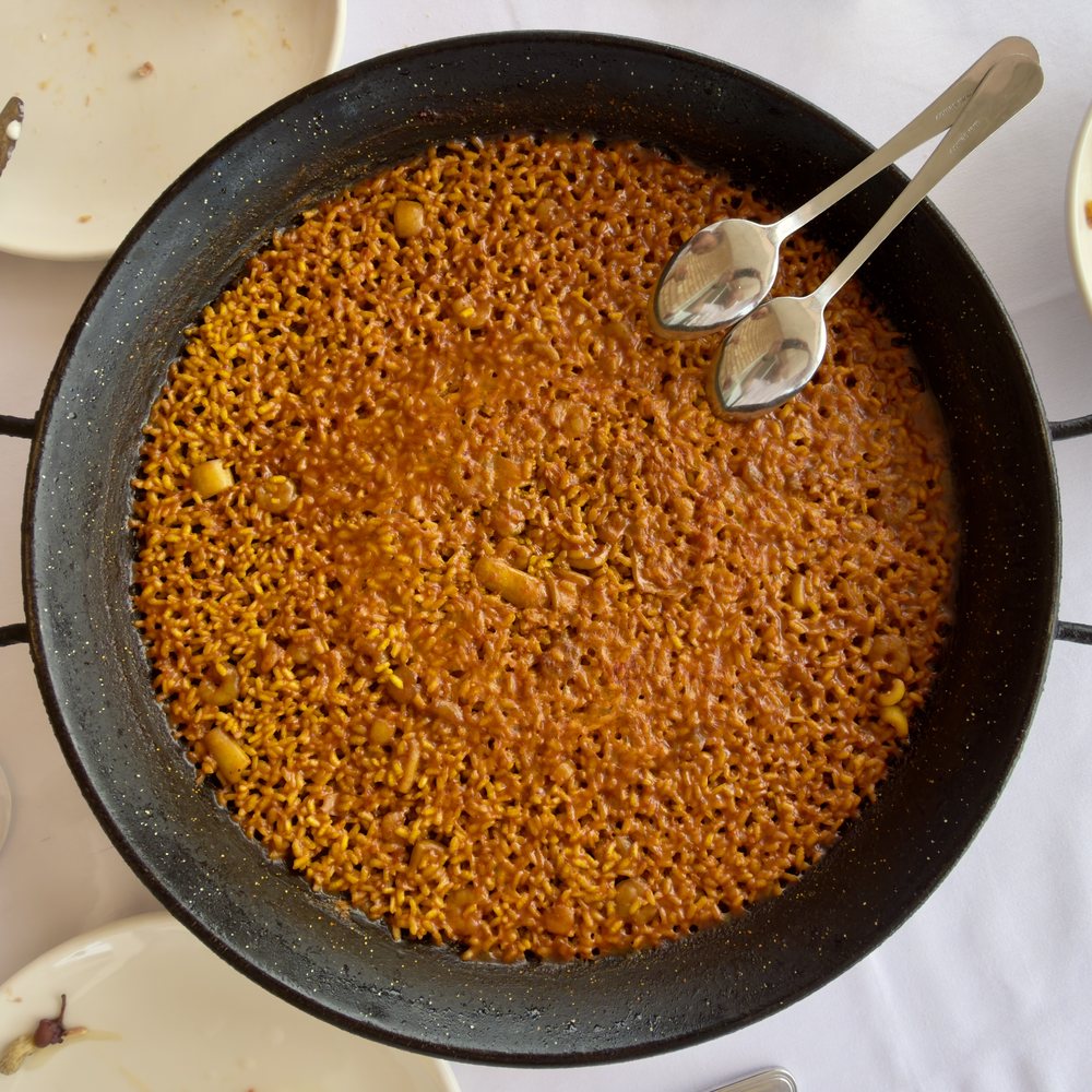 Arroz del senyoret: тонкий слой риса в широкой сковороде, морепродукты уже очищены. Фото: Alvy, CC BY 4.0, Wikimedia Commons